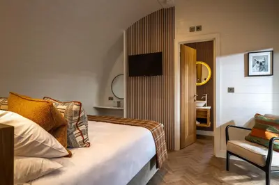 a bedroom with a bed and a chair and a television at POD St Ives - LUXURY GLAMPING ACCOMMODATION in St Ives