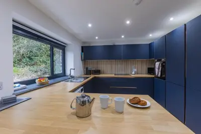 a kitchen with blue cabinets and a table with a plate of food at Manor in Bude
