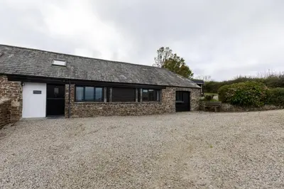 a stone house with a garage and a driveway at Manor in Bude