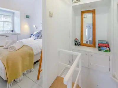 a white bedroom with a bed and a mirror at Fishermans Cottage in St Ives