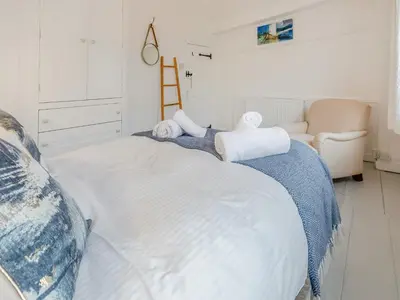a bedroom with a large white bed and a chair at Fishermans Cottage in St Ives