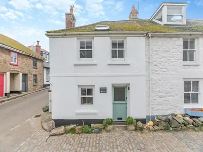 a white house with a blue door on a street at Fishermans Cottage in St Ives