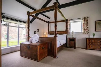 a bedroom with a canopy bed in a room with windows at Bligh - Treworgie Barton Cottages in Bude