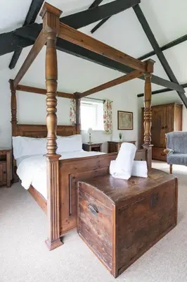 a bedroom with a large wooden bed with a wooden trunk at Bligh - Treworgie Barton Cottages in Bude