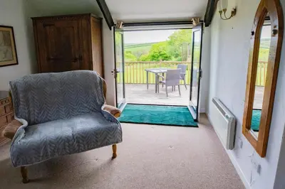 a living room with a chair and a patio at Bligh - Treworgie Barton Cottages in Bude
