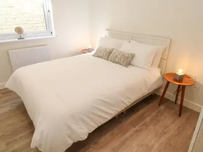 a bedroom with a large white bed with a table at 2 The Dunes in Falmouth