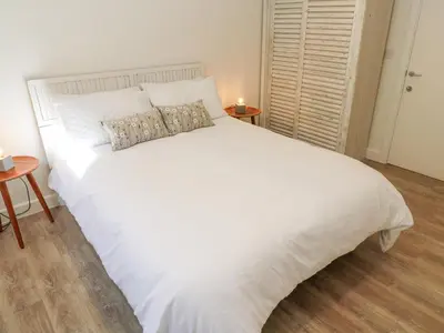 a large white bed in a bedroom with two tables at 2 The Dunes in Falmouth