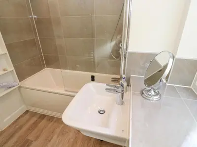 a bathroom with a sink and a shower with a mirror at 2 The Dunes in Falmouth