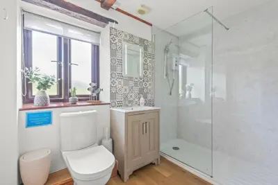 a white bathroom with a toilet and a shower at The Dairy in Liskeard