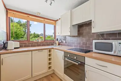 a kitchen with white cabinets and a microwave at The Dairy in Liskeard