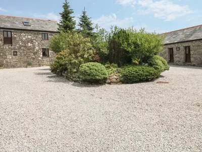 a stone building with bushes in front of a yard at The Dairy in Liskeard