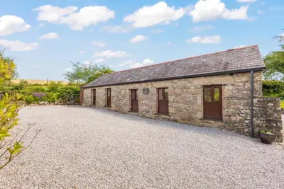 an old stone cottage with a gravel driveway at The Stables in Liskeard