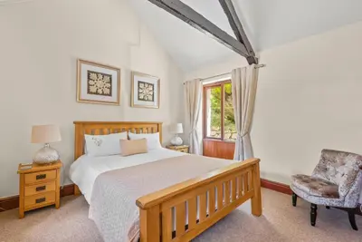 a bedroom with a bed and a chair and a window at The Stables in Liskeard