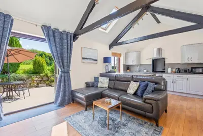 a living room with a leather couch and a table at The Stables in Liskeard