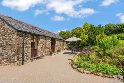 a stone building with a table and an umbrella at The Stables in Liskeard