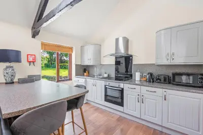 a kitchen with white cabinets and a counter top at The Stables in Liskeard
