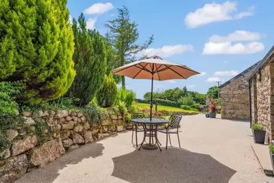 a table and chairs with an umbrella on a patio at The Stables in Liskeard