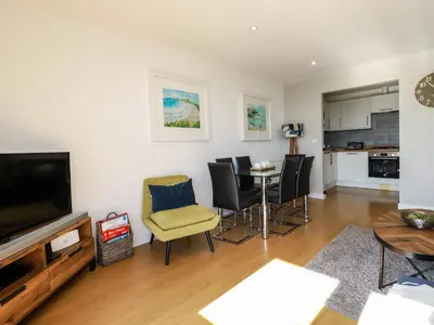 a living room with a tv and a table and chairs at 33 Tre Lowen in Newquay