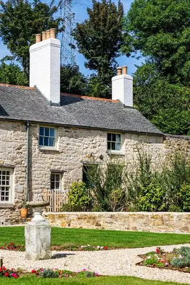 a stone house with two chimneys on top of it at Manor Cottage at Cusgarne Manor, romantic, dog-friendly in Cusgarne