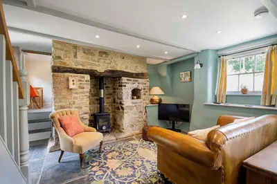 a living room with a couch and a stone fireplace at Manor Cottage at Cusgarne Manor, romantic, dog-friendly in Cusgarne
