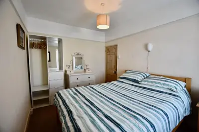 a bedroom with a bed and a dresser and a mirror at Morning Cottage in St Ives