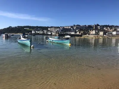 two boats sitting in the water on a beach at Morning Cottage in St Ives