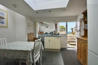 a kitchen and dining room with a table and a window at Morning Cottage in St Ives
