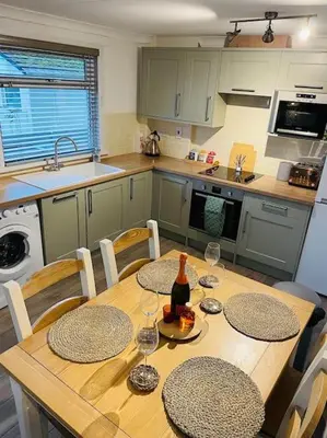 a kitchen with a table with chairs and a bottle of wine at The Lookout in Carbis Bay