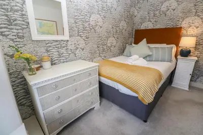 a small bedroom with a bed and a dresser at Apple Tree Cottage in Helston