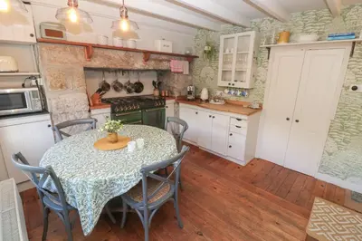 a kitchen with a table and chairs and a stove at Apple Tree Cottage in Helston