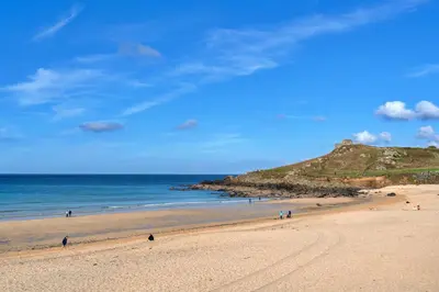 a beach with people walking on the sand and the ocean at Finest Retreats - No 6 Porthgwidden in St Ives