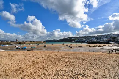 a beach with people in the water and buildings at Finest Retreats - No 6 Porthgwidden in St Ives