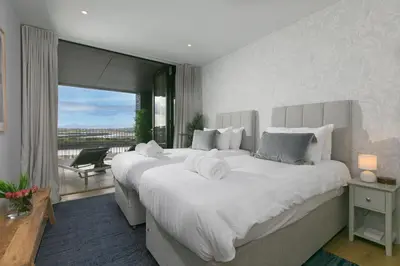 a bedroom with two large white beds and a balcony at 14 An Garth in Hayle