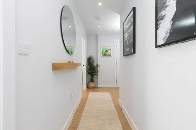 a hallway with white walls and a mirror at 14 An Garth in Hayle