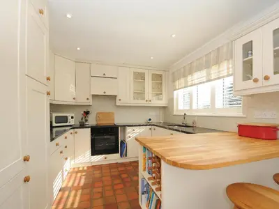 a kitchen with white cabinets and a wooden counter top at Trestar in Wadebridge