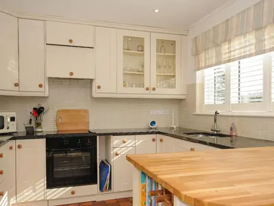 a kitchen with white cabinets and black appliances at Trestar in Wadebridge
