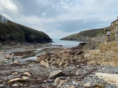 a rocky beach with a building and the ocean at Little Barn in Bodmin