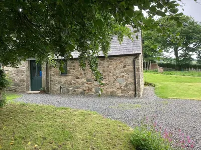 a stone house with a green door and a yard at Little Barn in Bodmin