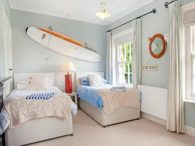 a bedroom with two beds and a surfboard on the wall at Lynwood in Boscastle