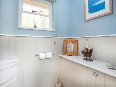 a bathroom with white walls and a window and shelves at Lynwood in Boscastle