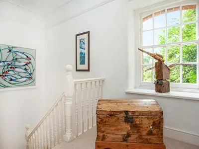 a white room with stairs and a window and a wooden trunk at Lynwood in Boscastle