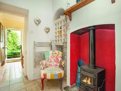 a room with a chair and a wood stove at Lynwood in Boscastle
