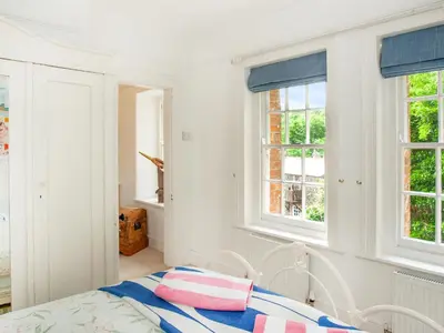 a white bedroom with a bed and windows at Lynwood in Boscastle