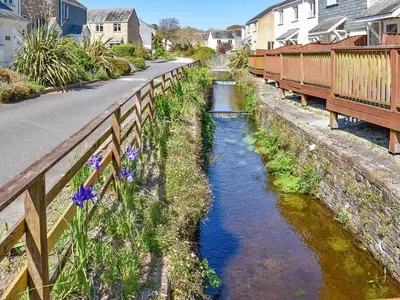 a river next to a road with a bridge at Dreckly in Falmouth