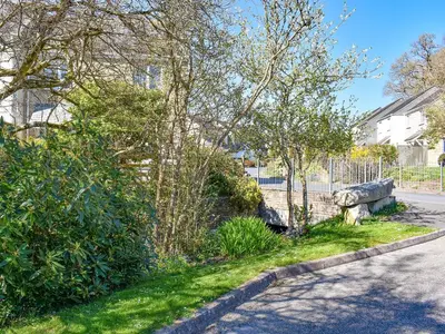 a street with a fence and trees on the side of a road at Dreckly in Falmouth