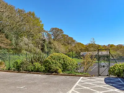 a tennis court with a gate in a parking lot at Dreckly in Falmouth