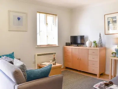 a living room with a couch and a tv on a dresser at Dreckly in Falmouth