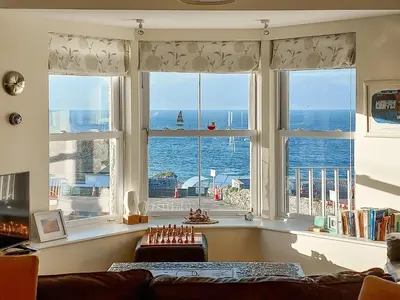 a living room with a large window with a view of the ocean at Ocean Breezes in St Ives