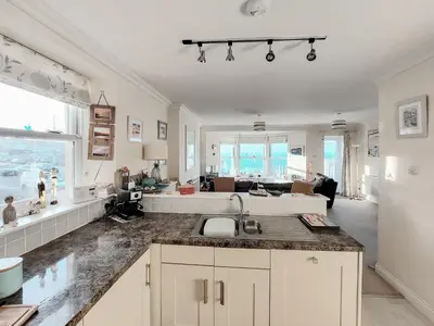 a kitchen with a sink and a living room at Ocean Breezes in St Ives