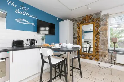 a kitchen with a table and chairs and a mirror at The Old Salthouse in St Ives